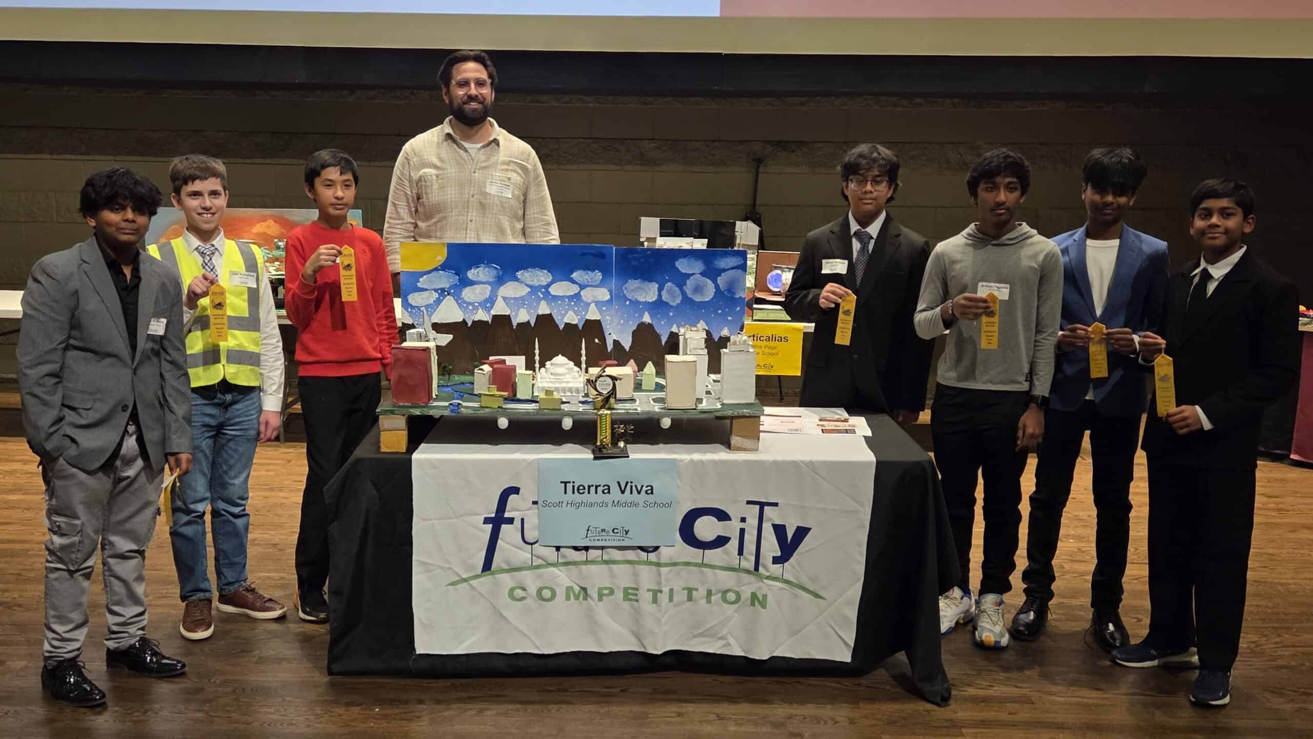Students pose with a "Future City" model at a competition, holding trophies and smiling.