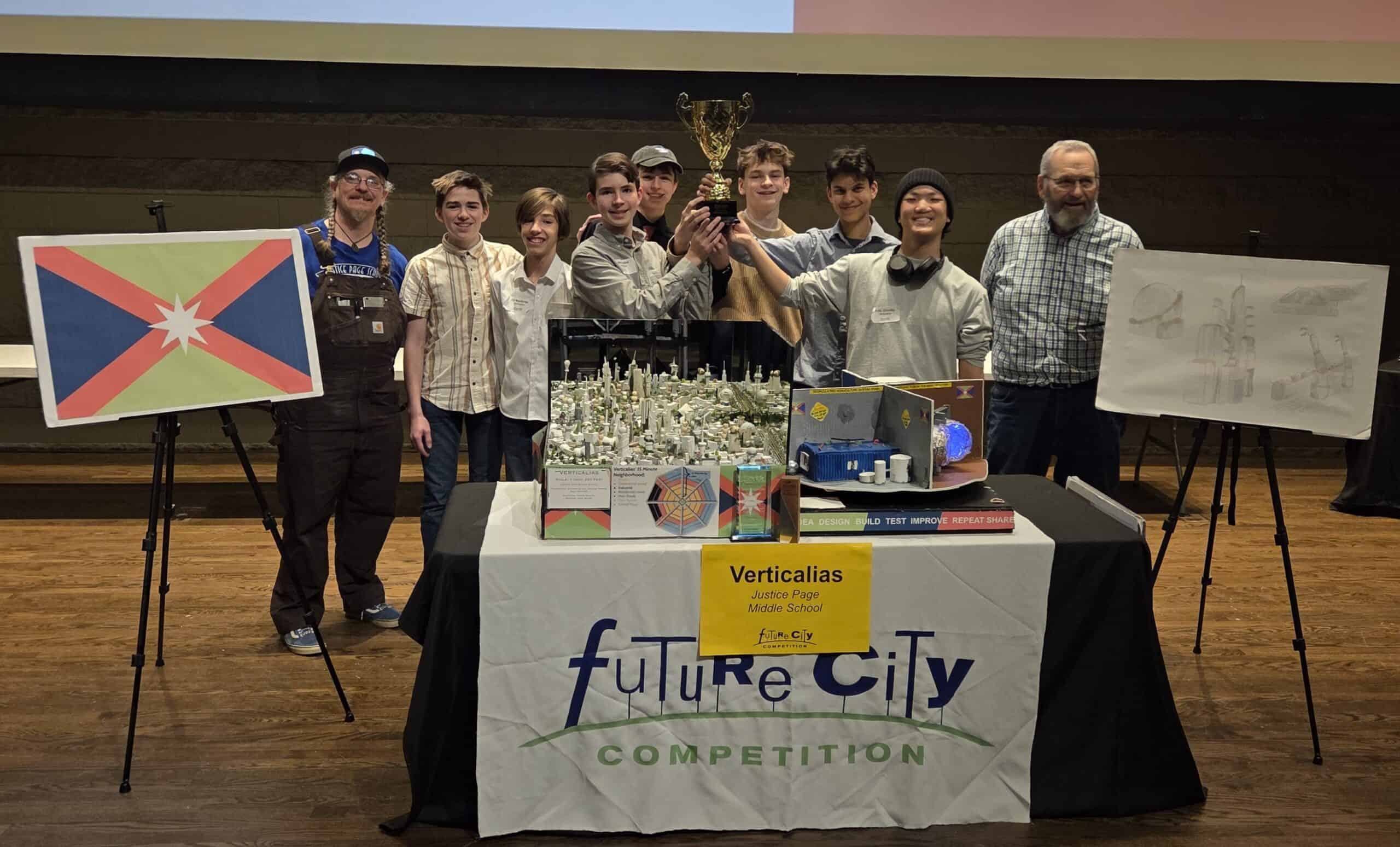 A group of nine people posing with a trophy at a Future City Competition event table.